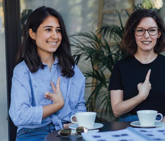 Two women using their hands to sign Auslan language