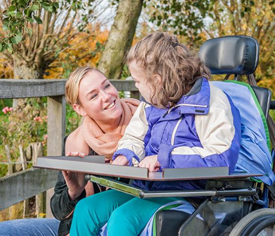 Young woman talking to girl in a wheelchair