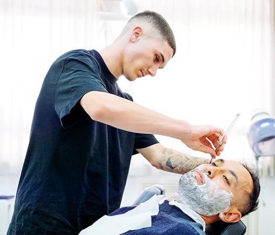 Decorative image - barbering student shaving a client 