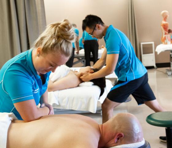 Decorative image - massage students working in live work clinic