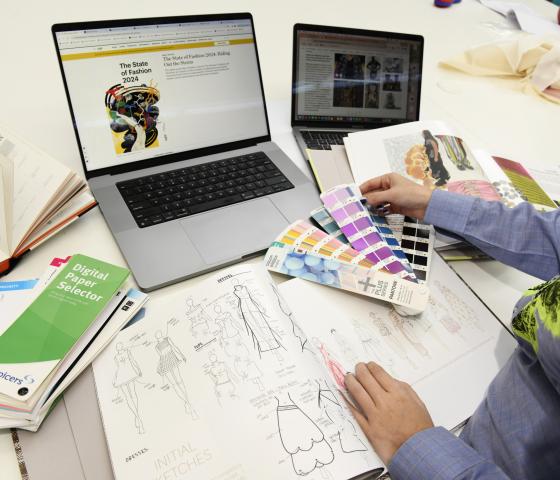 A person at a table with drawings and colour swatches
